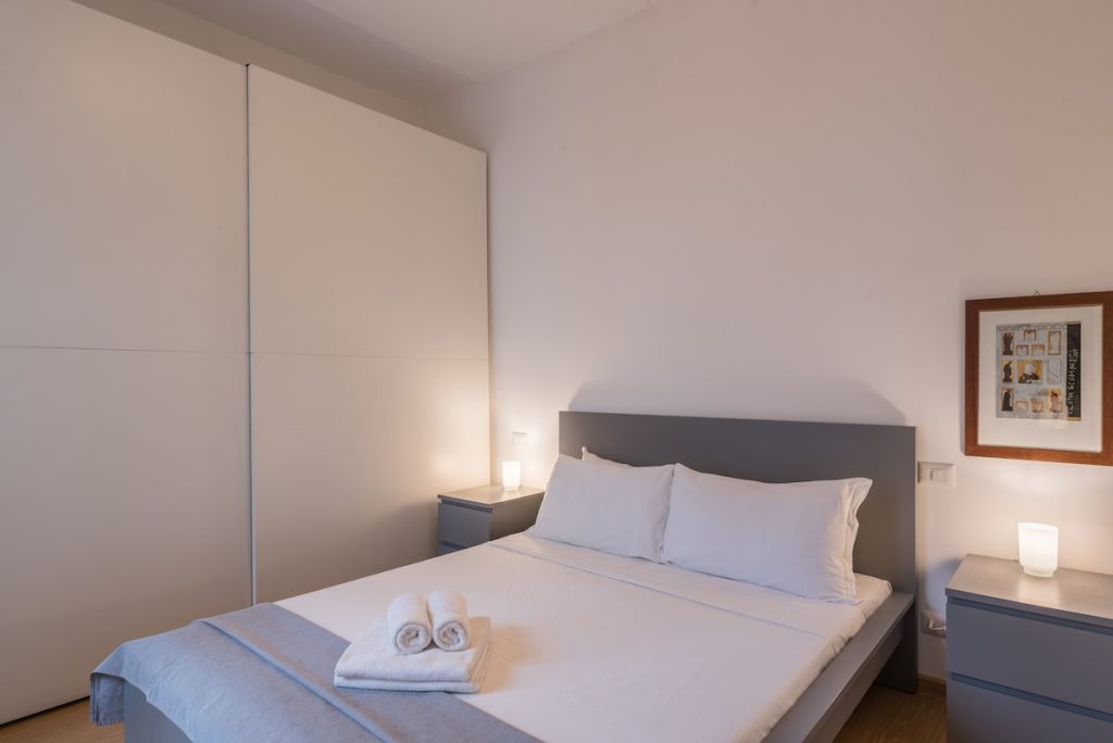 La camera da letto con il letto matrimoniale, i comodini e l'armadio bianco a tutta altezza
